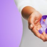 healthcare and social problems concept - close up of woman hands holding purple domestic violence awareness ribbon over violet background