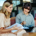 Two women sitting together reviewing paperwork