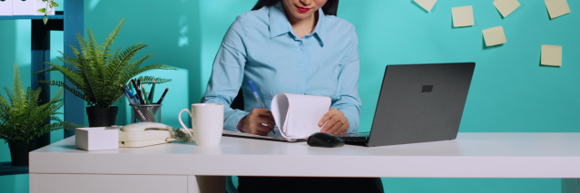Woman at a desk writing on a notepad