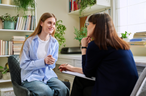 Smiling young teenage female patient talking to a female therapist