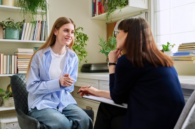Smiling young teenage female patient talking to a female therapist