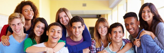 Group Of High School Students Giving Piggybacks In Corridor