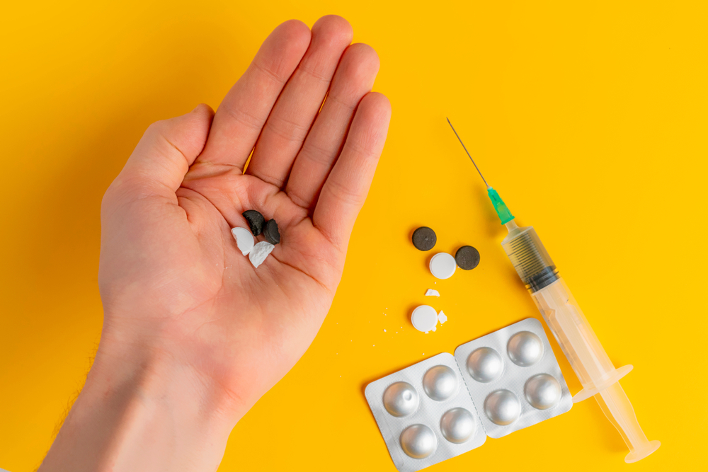 doping tablets and syringes flat lay and hand holding it