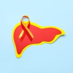 Awareness ribbon with paper liver on blue background. Hepatitis concept