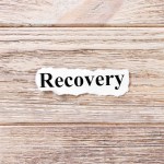 Recovery of the word on paper. concept. Words of Recovery on a wooden background.