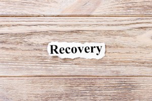 Recovery of the word on paper. concept. Words of Recovery on a wooden background.
